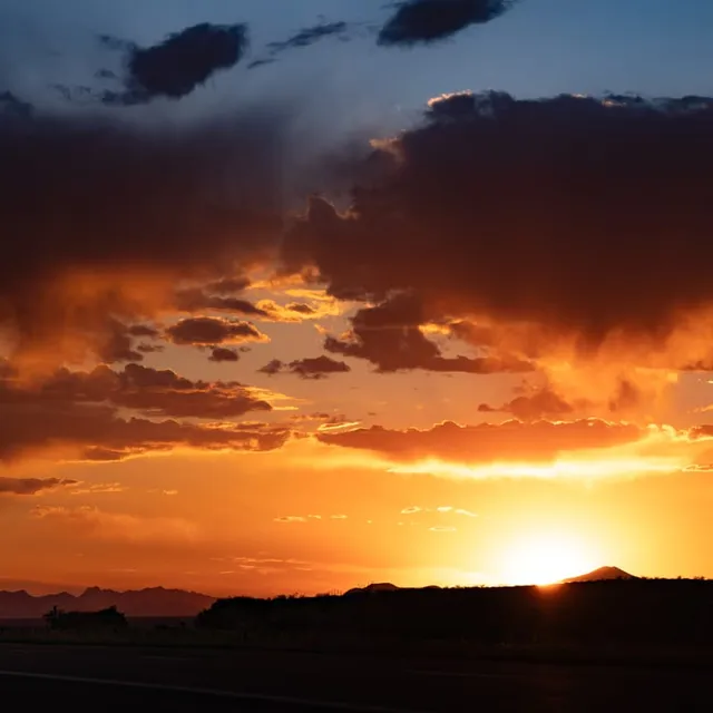 Semi Truck With Headlights On Under a Fiery Sunset