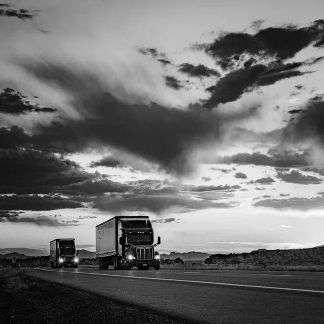 Semi Trucks Under Orange Storm Clouds at Sunset